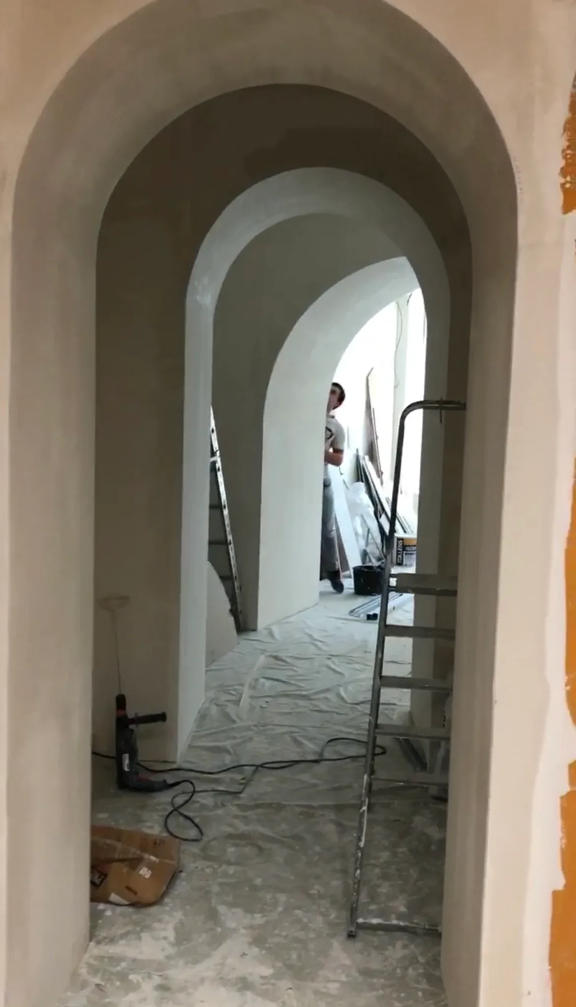 Chantier : enfilade d’arches arrondies en cours d’enduit, un escabeau au premier plan